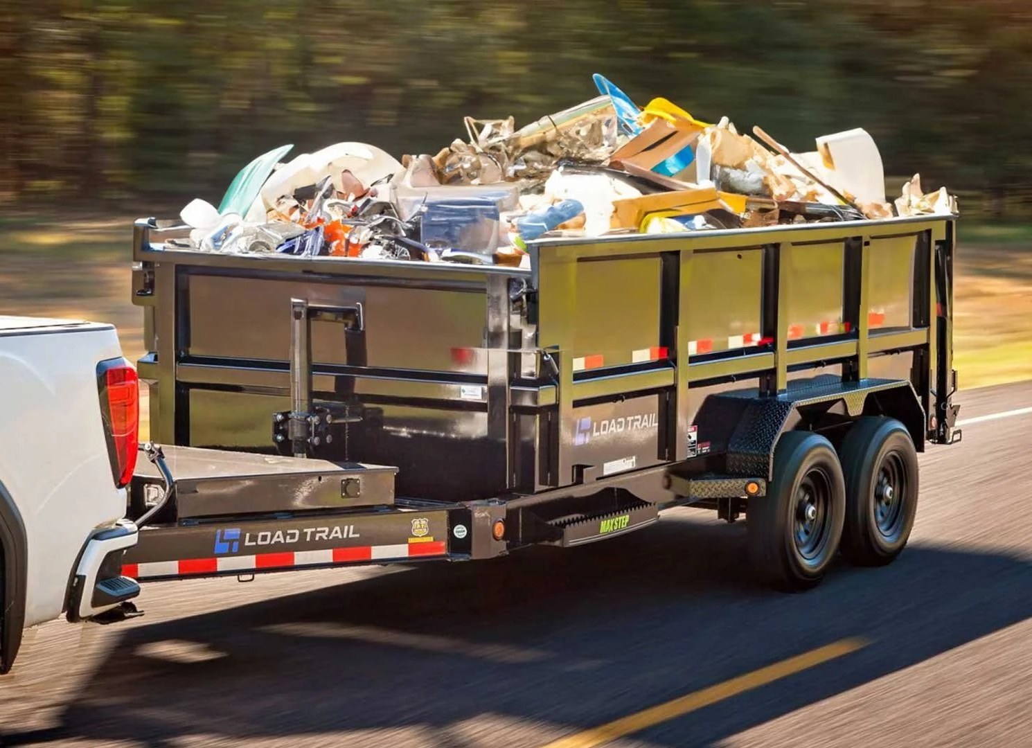 Pickup truck towing a trailer piled high with junk and debris